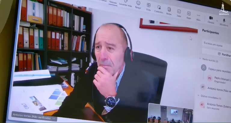 António Torres a participar por videoconferência numa reunião municipal, sentado no gabinete, com auscultadores, durante uma apresentação sobre transportes públicos.