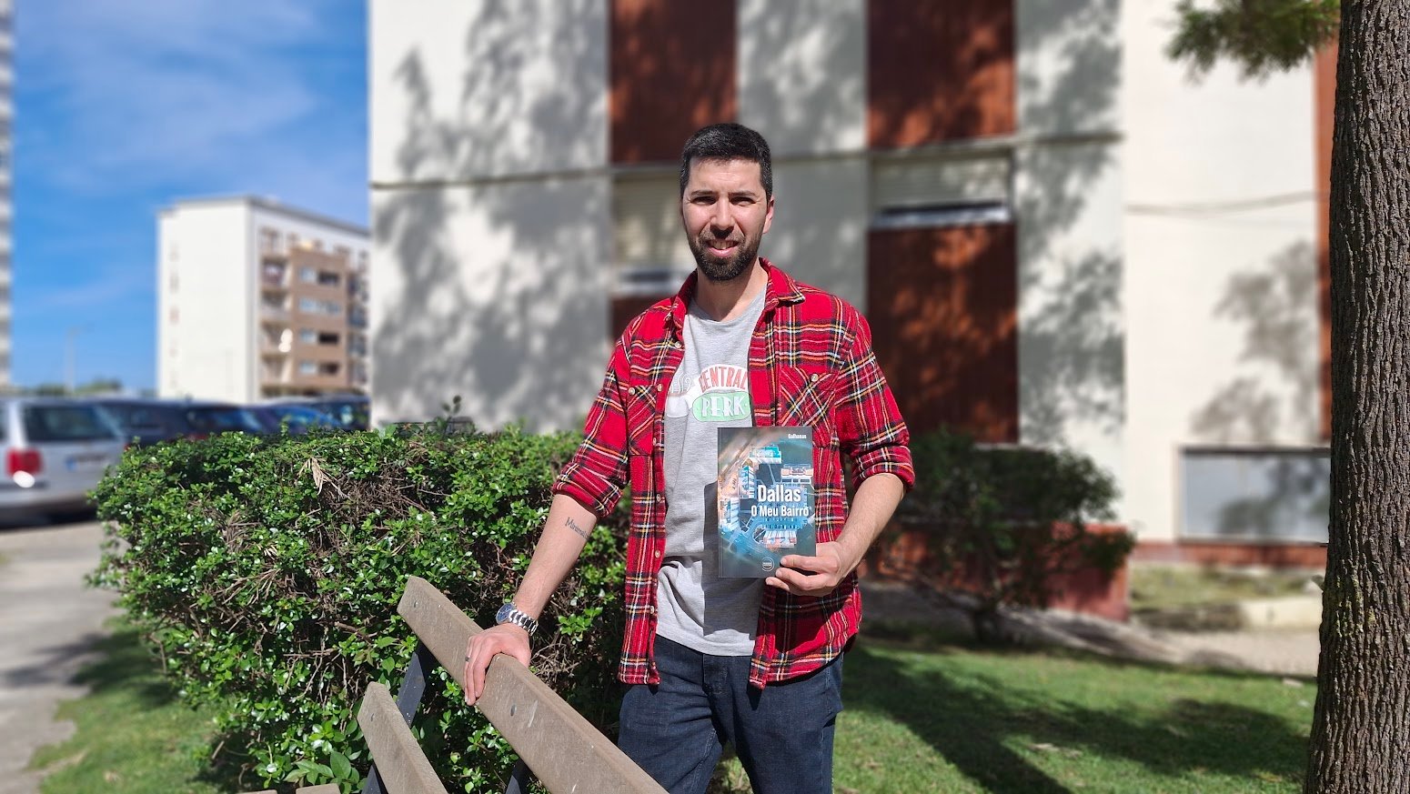 Fábio Galhanas posa no Carregado segurando o livro “Dallas – O Meu Bairro”, junto a um espaço verde da urbanização da Barrada.