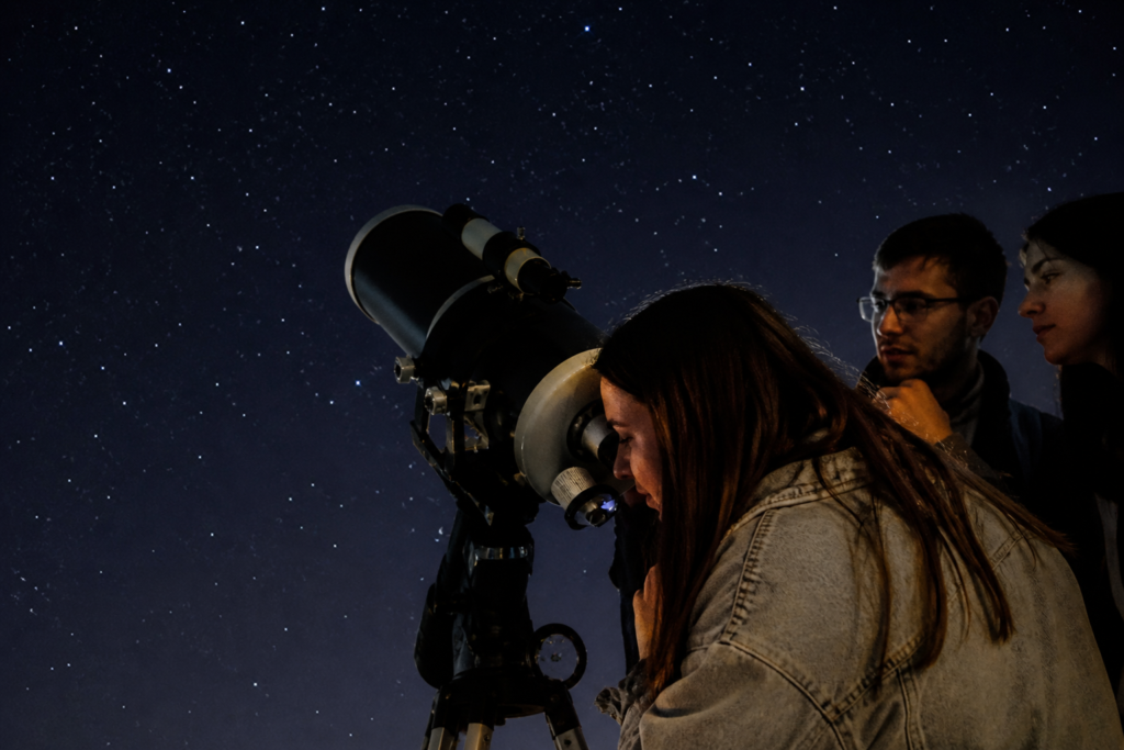 Pessoas a observar o céu noturno através de um telescópio durante uma sessão de astronomia