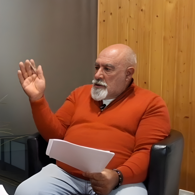 Carlos Fonte sentado durante uma entrevista, a falar e a gesticular com documentos na mão