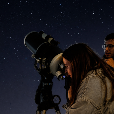 Pessoas a observar o céu noturno através de um telescópio durante uma sessão de astronomia